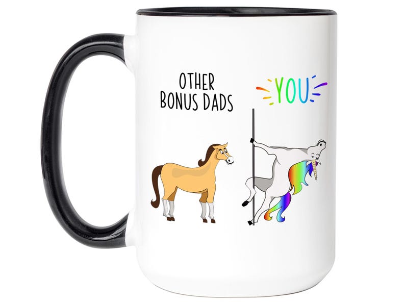 May include: White ceramic mug with a black handle and rim. The mug features the text "OTHER BONUS DADS" and the word "YOU" in rainbow colors. Illustrations of a horse and a unicorn are also on the mug.