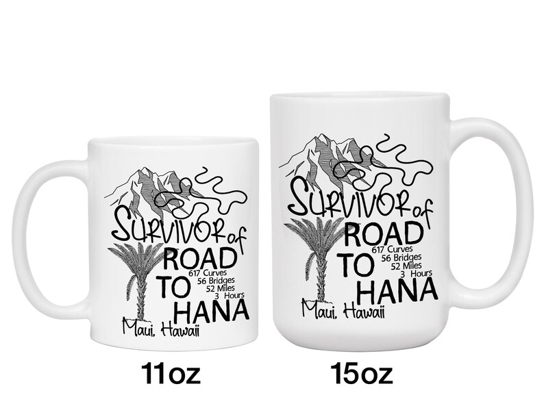 K&ouml;nnte beinhalten: Zwei wei&szlig;e Keramikbecher mit schwarzem Text und Illustrationen. Der Text lautet "Survivor of Road to Hana" mit Details &uuml;ber die Stra&szlig;e. Ein Becher ist 312 ml, der andere 425 ml. Das Design umfasst Berge und eine Palme.