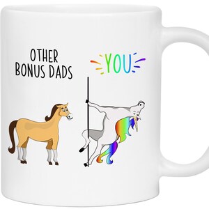 May include: White ceramic mug with a humorous design. The mug features the text "OTHER BONUS DADS" and "YOU" with a rainbow accent. The design includes a cartoon horse and a unicorn pole dancing.