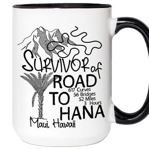 K&ouml;nnte beinhalten: Wei&szlig;er Keramikbecher mit schwarzem Henkel und Rand. Der Becher zeigt eine schwarz-wei&szlig;e Grafik von Bergen, einer Palme und dem Text "Survivor of Road to Hana, Maui, Hawaii". Enth&auml;lt Statistiken &uuml;ber die Stra&szlig;e.
