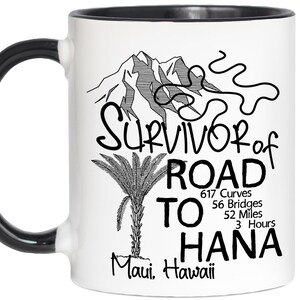 K&ouml;nnte beinhalten: Wei&szlig;er Keramikbecher mit schwarzem Griff und Rand. Der Becher zeigt eine schwarz-wei&szlig;e Grafik eines Berges, einer Palme und den Text "Survivor of Road to Hana, Maui, Hawaii". Der Text enth&auml;lt die Anzahl der Kurven, Br&uuml;cken, Meilen und Stunden.