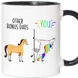 May include: White ceramic mug with a black handle and rim. The mug features a humorous illustration with the text "OTHER BONUS DADS" and "YOU". The illustration depicts a horse and a unicorn, with the unicorn pole dancing.