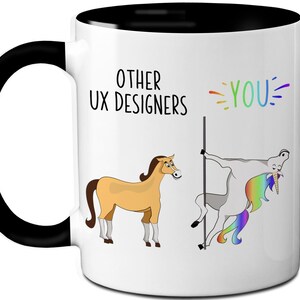 May include: White ceramic mug with a black handle and interior. The mug features a humorous illustration comparing "Other UX Designers" to a horse and "YOU" to a unicorn, with text in black and rainbow colors.