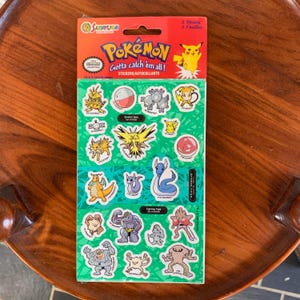 May include: A sheet of Pokémon stickers featuring various characters and the phrase "Gotta catch 'em all!". The stickers are on a green background with a red header. The package includes 2 sheets of stickers.