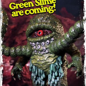 Op de afbeelding: Een groen, slijmerig monster met meerdere ogen en &eacute;&eacute;n groot rood oog. Het monster heeft lange, groene armen en draagt een rok van groene slijm. De tekst "The Green Slime are coming!" staat in gele letters op een rode achtergrond.