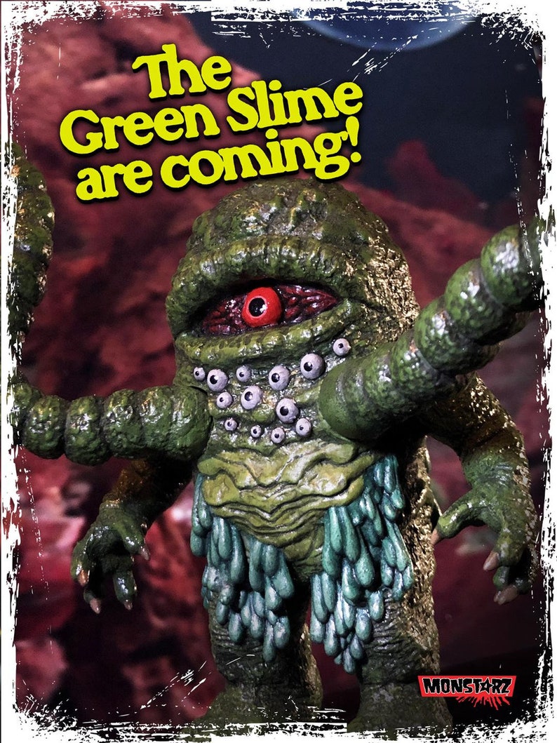 Op de afbeelding: Een groen, slijmerig monster met meerdere ogen en &eacute;&eacute;n groot rood oog. Het monster heeft lange, groene armen en draagt een rok van groene slijm. De tekst "The Green Slime are coming!" staat in gele letters op een rode achtergrond.
