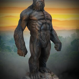 May include: A large, dark grey gorilla statue standing on a rocky base. The gorilla is depicted in a powerful pose with its arms at its sides and its head held high. The statue is made of a durable material and is suitable for outdoor use.