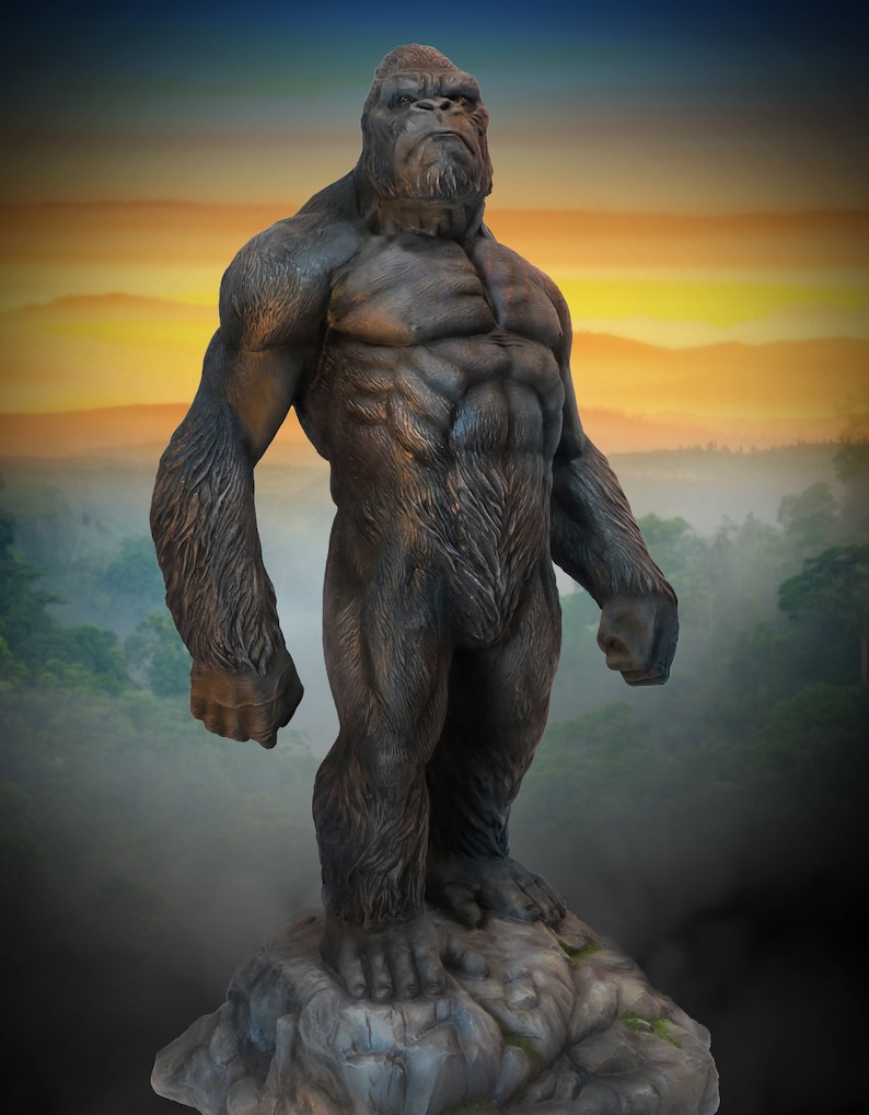 May include: A large, dark grey gorilla statue standing on a rocky base. The gorilla is depicted in a powerful pose with its arms at its sides and its head held high. The statue is made of a durable material and is suitable for outdoor use.