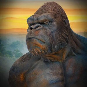 May include: A close-up of a large, dark brown gorilla statue with a serious expression. The statue is set against a backdrop of a colourful sunset and a misty forest.