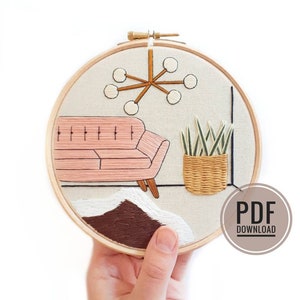 May include: Embroidered hoop art featuring a pink couch, a brown rug, a potted plant, and a light fixture with six white bulbs. The hoop is made of wood and has a white background.