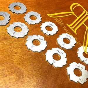 Puede incluir: Un juego de diez hojas de sierra de metal de color plateado con agujeros y dientes de diferentes tamaños. Las hojas están etiquetadas con los números del 1 al 10 y las palabras "mm" para milímetros.