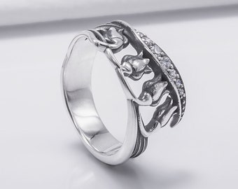 May include: A silver ring with a floral design featuring three stylized flowers with a row of clear cubic zirconia stones.