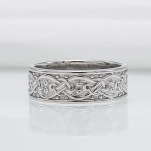 May include: A silver wedding band with a Celtic knot design.