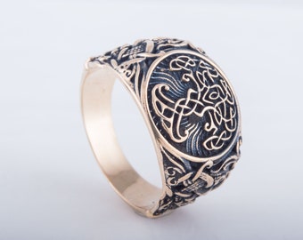 May include: A gold ring with a detailed design of a Celtic knot and other intricate patterns. The ring is made of metal and has a dark finish.