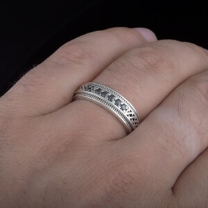 May include: A silver band ring with a row of black gemstones set in a decorative pattern.