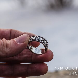 May include: A silver ring with a band of skulls around the circumference.
