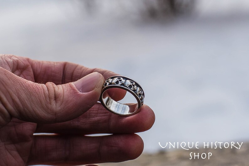 May include: A silver ring with a band of skulls around the circumference.