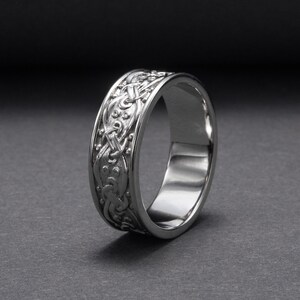May include: A silver wedding band with a Celtic knot design.