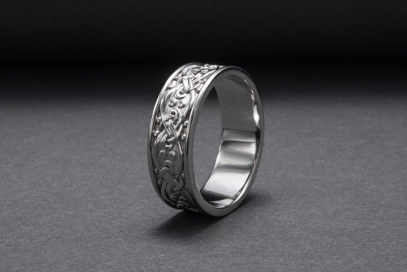 May include: A silver wedding band with a Celtic knot design.