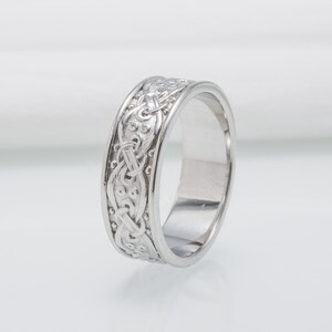 May include: A silver wedding band with a Celtic knot design.