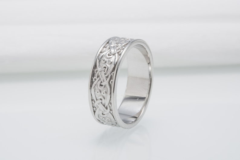 May include: A silver wedding band with a Celtic knot design.