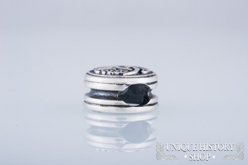Puede incluir: Cuentas de charm de plata con un dise&ntilde;o detallado y forma circular. La cuenta tiene un peque&ntilde;o agujero para sujetarla a una pulsera o collar.