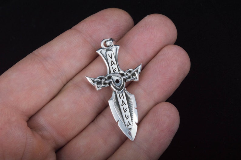 May include: Silver pendant in the shape of a sword with the word "Valhalla" inscribed on it.