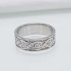 May include: A silver ring with a Celtic knot design. The knot is intricate and detailed, with small dots throughout the design.