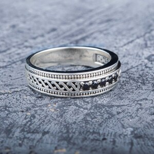 May include: A silver ring with a decorative design and black gemstones.