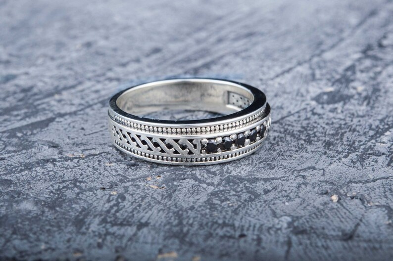 May include: A silver ring with a decorative design and black gemstones.