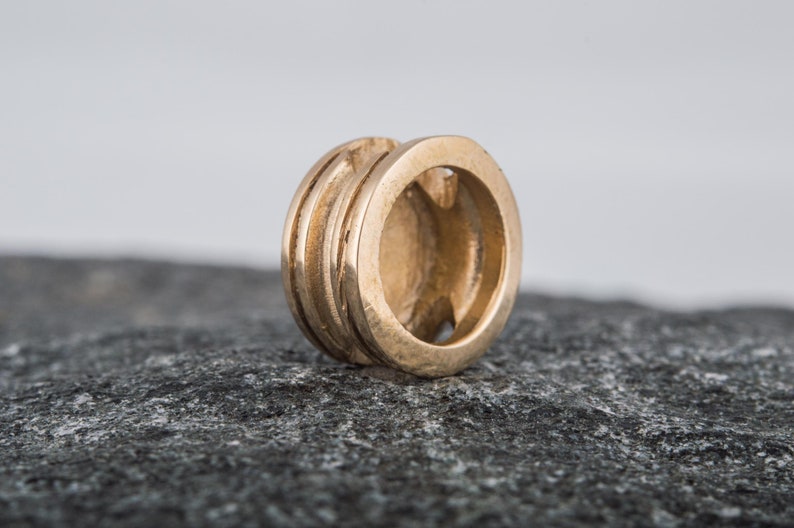 May include: A gold-colored metal bead with a circular design and a smooth, polished finish.