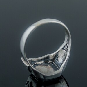 K&ouml;nnte beinhalten: Silberring mit quadratischer Fassung. Der Ring ist mit filigranen Designs an der Band und der Fassung verziert.