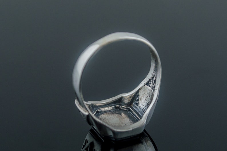 K&ouml;nnte beinhalten: Silberring mit quadratischer Fassung. Der Ring ist mit filigranen Designs an der Band und der Fassung verziert.