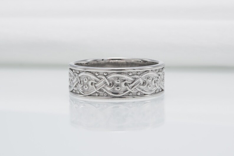 May include: A silver wedding band with a Celtic knot design.