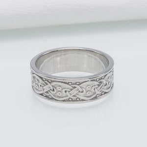 May include: A silver band ring with a Celtic knot design.