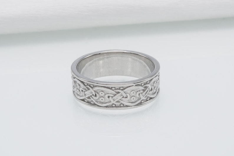 May include: A silver band ring with a Celtic knot design.