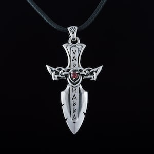 May include: Silver pendant necklace with a sword design featuring a red gemstone and the inscription "Valhalla".