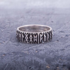 Op de afbeelding: Een zilveren ring met een band van verhoogde runen rond de omtrek.