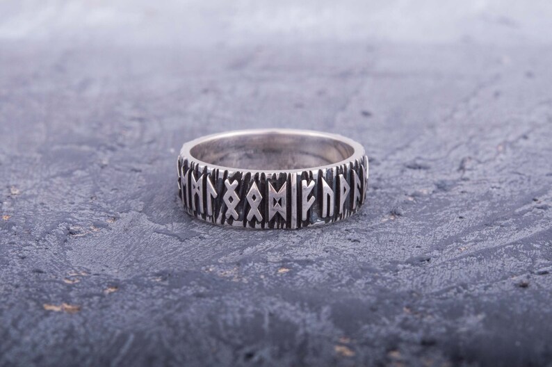 Op de afbeelding: Een zilveren ring met een band van verhoogde runen rond de omtrek.