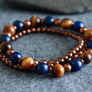 May include: A triple-strand bracelet with copper beads, tiger's eye beads, and lapis lazuli beads.