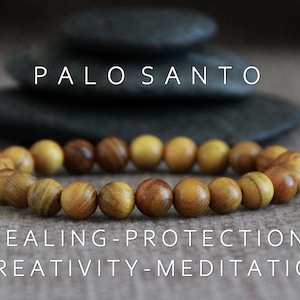 Op de afbeelding: Een armband van lichtbruine houten kralen. Het woord PALO SANTO wordt boven de armband weergegeven, met daaronder de woorden HEALING, PROTECTION, CREATIVITY en MEDITATION. Donkergrijze stenen zijn op de achtergrond.