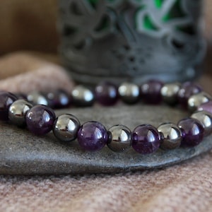 May include: A purple amethyst and hematite beaded bracelet. The bracelet is made with alternating purple amethyst and silver hematite beads.