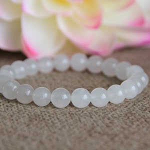 May include: White gemstone bracelet with round beads. The bracelet is made of natural white stones and is a simple and elegant piece of jewelry.