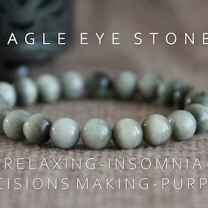 Op de afbeelding: Een armband met ronde, lichtgroene kralen van adelaarsoogsteen. De tekst 'EAGLE EYE STONE' staat bovenaan en 'RELAXING-INSOMNIA-DECISIONS MAKING-PURPOSE' onderaan. De armband ligt op een neutrale achtergrond.