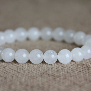 May include: White gemstone bracelet with round beads. The bracelet is made of natural white stones and is a simple and elegant design.