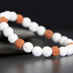 May include: White and brown beaded bracelet with a textured white bead design. The bracelet is made of lava rock and rudraksha beads.