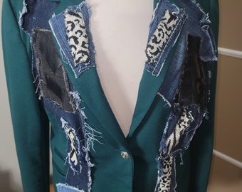 May include: A dark green blazer with a single button closure. The blazer is decorated with patches of denim, black fabric, and white and black patterned fabric.