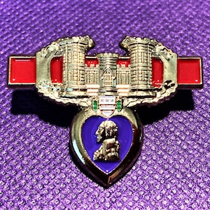 May include: A gold-colored military pin with a purple heart and a castle design. The pin has a red enamel bar with white stars.