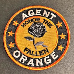 May include: A black and orange embroidered patch with a black rose and the text "AGENT HONOR THE FALLEN ORANGE" surrounded by five gold stars.