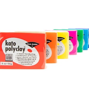 May include: A row of colorful Kato Polyclay packages, each displaying the brand name and product details. The packages are in various colors, including red, orange, yellow, pink, green, blue, purple, and neutral tones. Each package is 2 oz (56g).